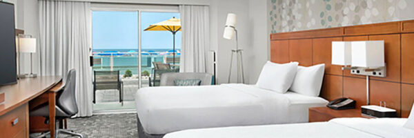 hotel room with beds and balcony view of the ocean