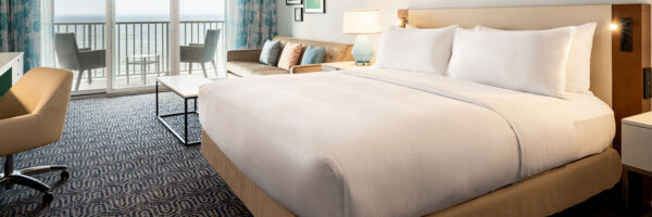 hotel room with king bed and balcony window view of the ocean